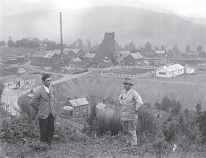 Joseph Divis and a companion overlooking the headworks for the Blackwater mine at Waiuta. The prominent mullock (waste) heap in the centre had been levelled to provide a bowling green.